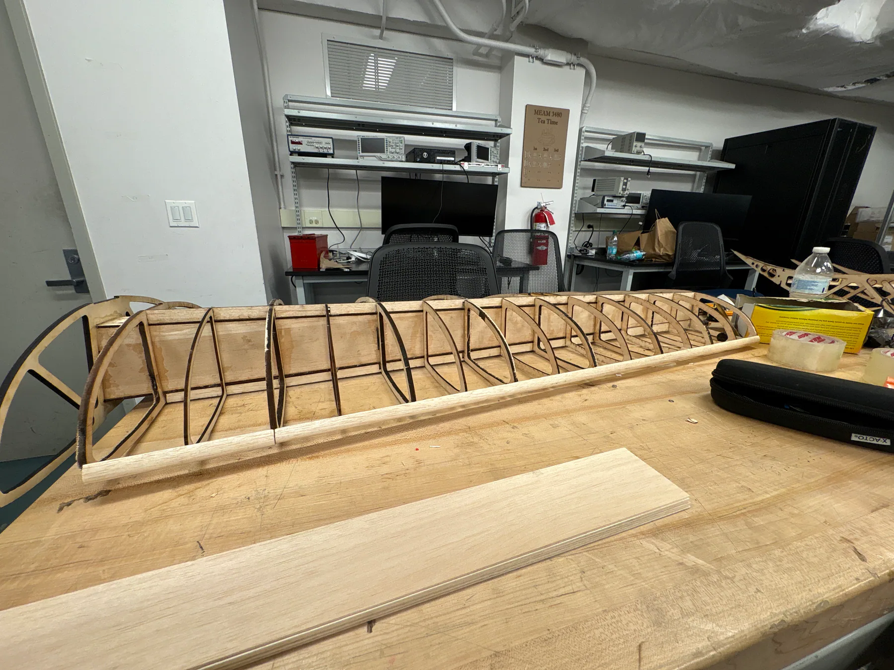 Exposed balsa and plywood wing structure on a workbench.
