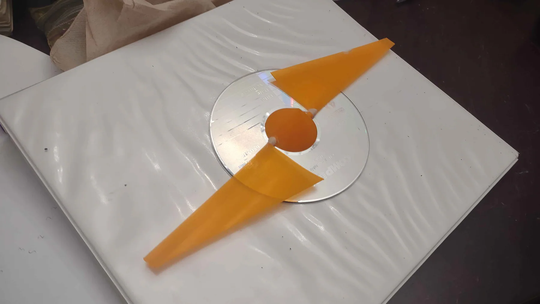Orange two-blade wind turbine on a circular test mount.
